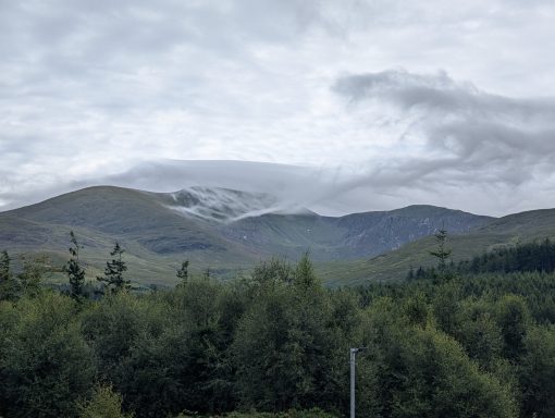 View over forestry of a mountain valley with thick clouds capping the mountain.