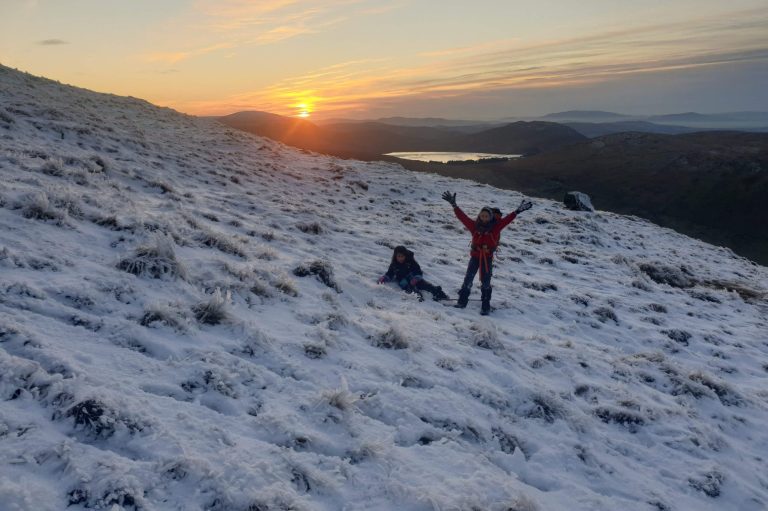 Children on a snowy mountain at sunset